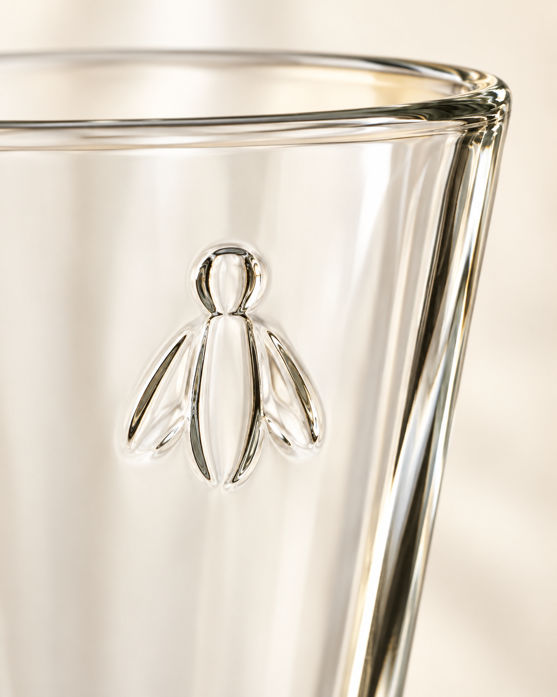 Detailed macro shot of the authentic French pressed glass Napoleonic bee symbol on La Rochere luxury glassware