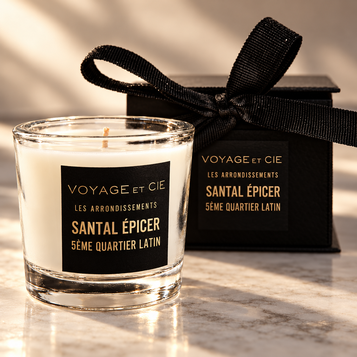 Close-up of the clear glass, wax and black-and-gold label of the Santal Épicé votive candle